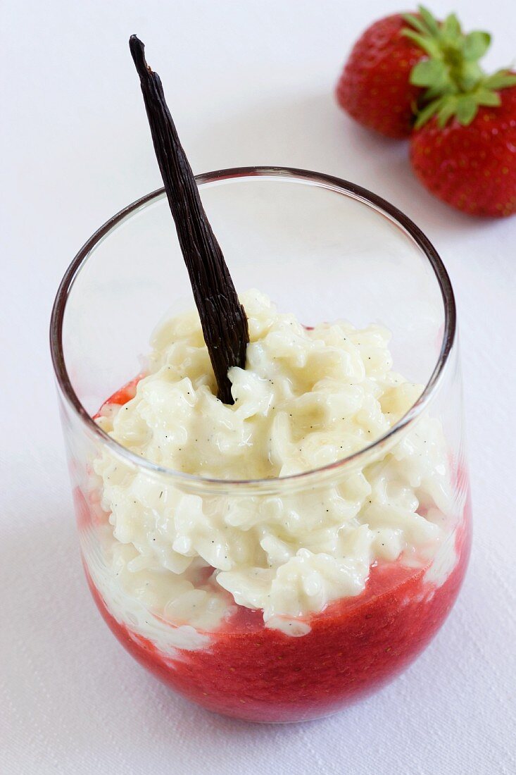Rice pudding with strawberry sauce and a vanilla pod