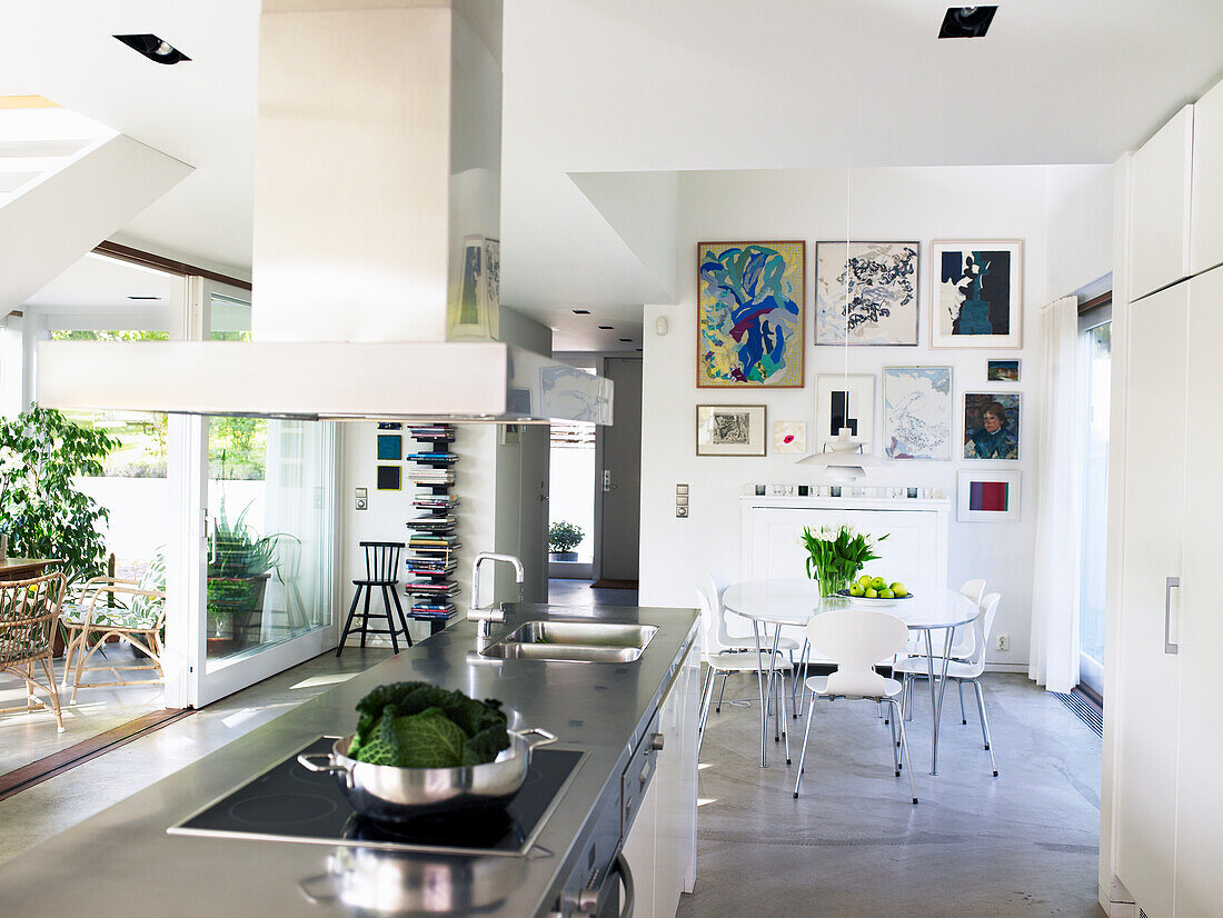 Moderne Küche mit Kochinsel und Essbereich, Kunst an den Wänden