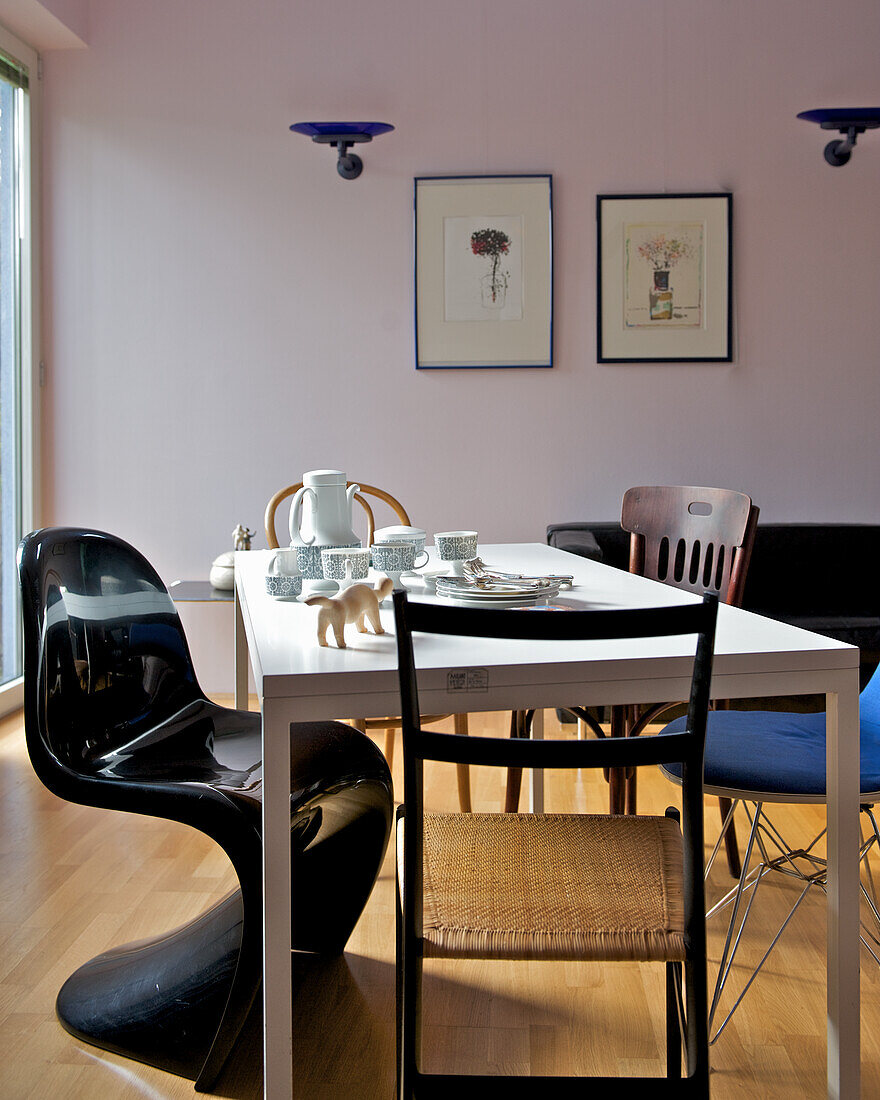 Dining room with white table and various chairs, murals and subtle lighting