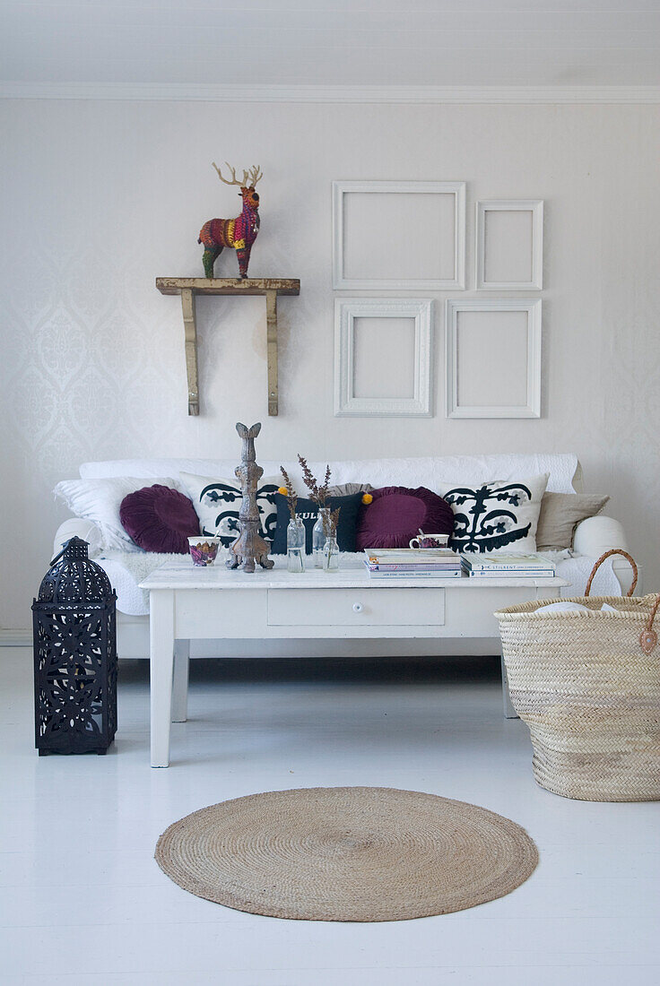 White couch with decorative cushions and picture frames on the wall