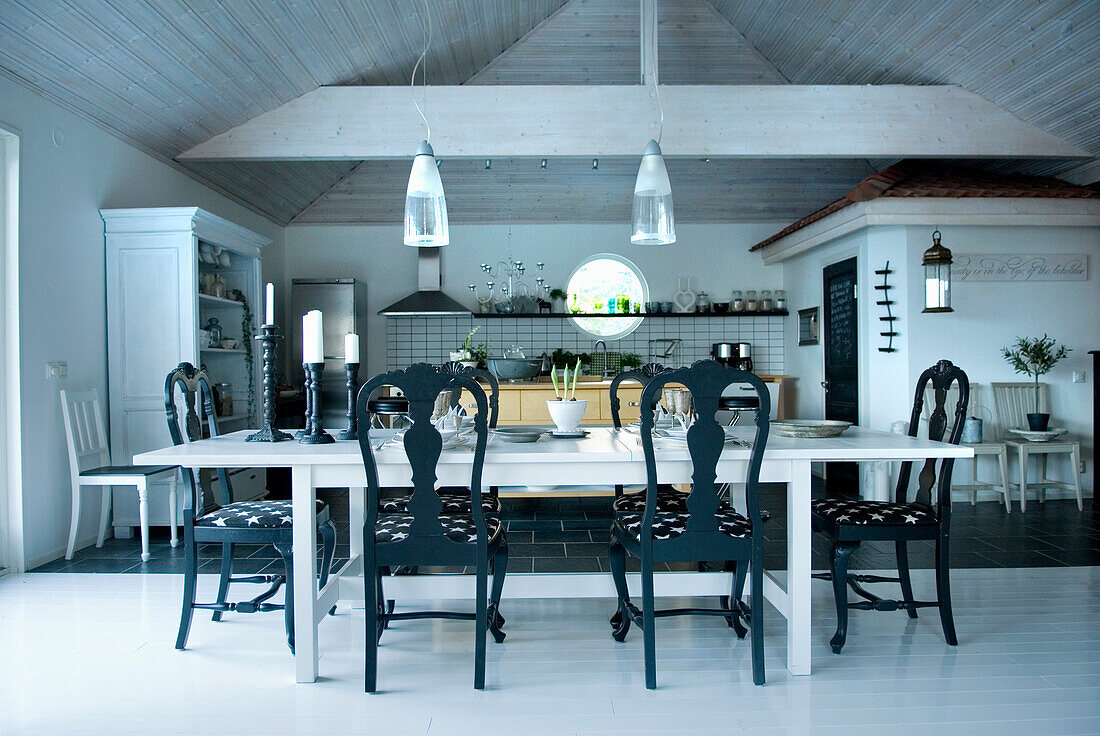 Großzügiges Esszimmer im Landhausstil mit weißem Holztisch und schwarzen Stühlen