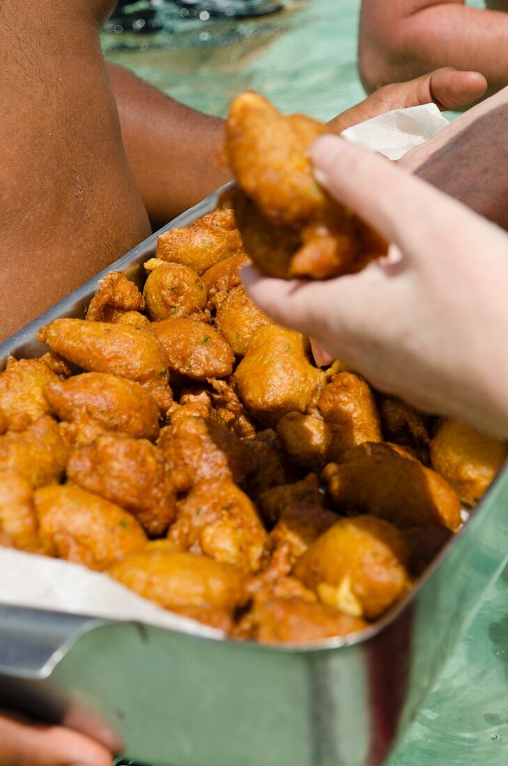 Person proffering cod fritters (Martinique)