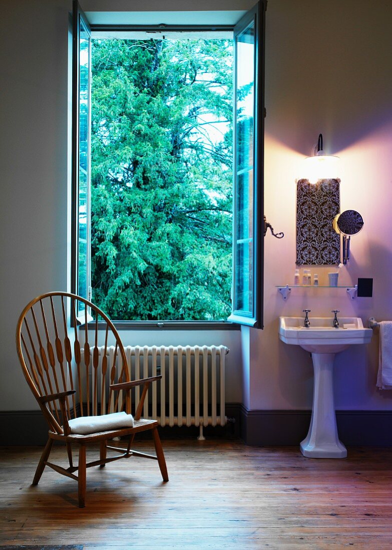 Wooden chair in front of open window in traditional bathroom