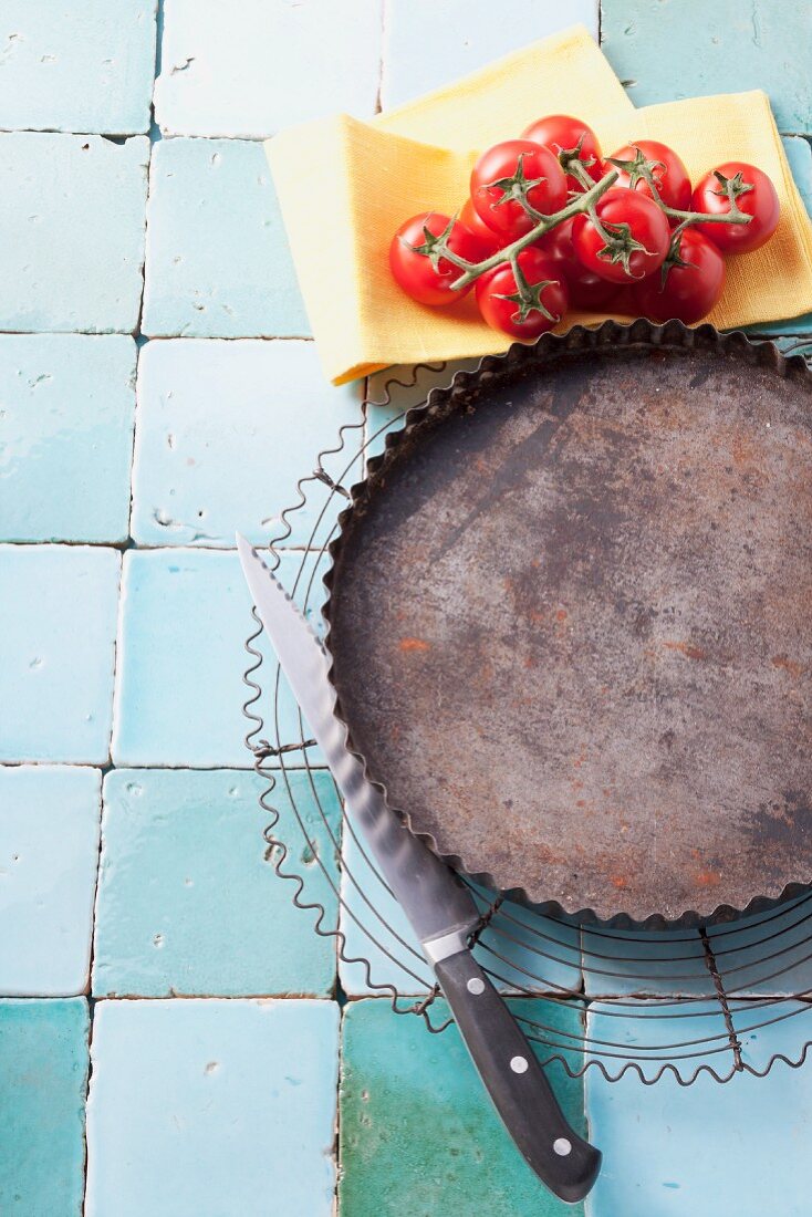 Empty tart tin on wire rack with tomatoes