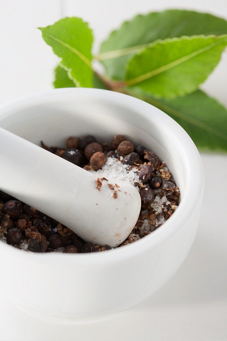 Mortar with spices and bay leaves in background