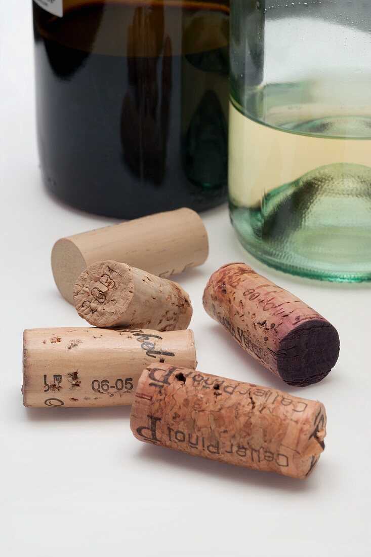 Verschiedene Weinkorken vor Rotwein- und Weissweinflaschen