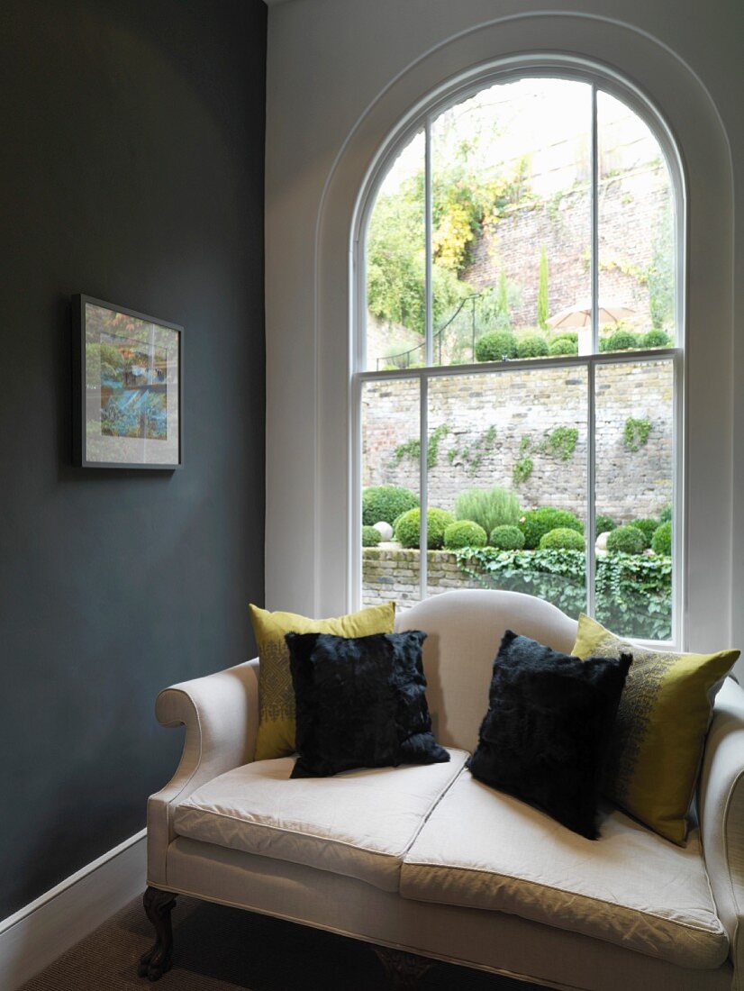 Sofa with cushions in front of arched window