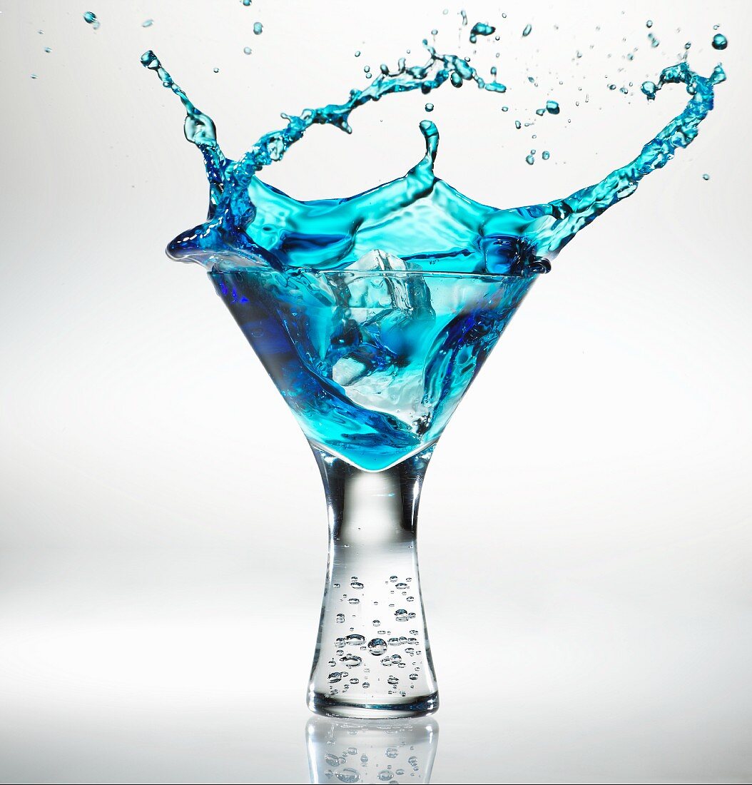 Eiswürfel fällt in ein Glas Blue Martini