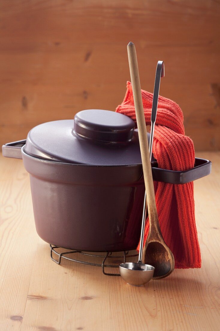 A cooking pot, a wooden spoon and a ladle