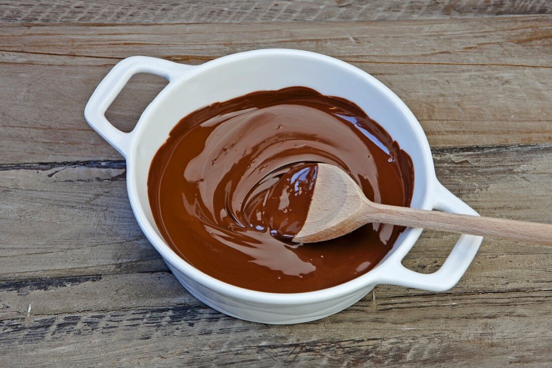 A wooden spoon in a bowl of melted chocolate