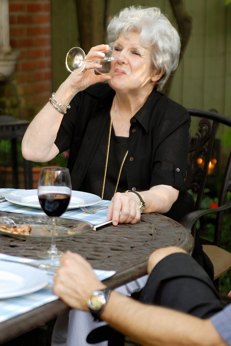Frau trinkt ein Glas Wein auf Terrasse