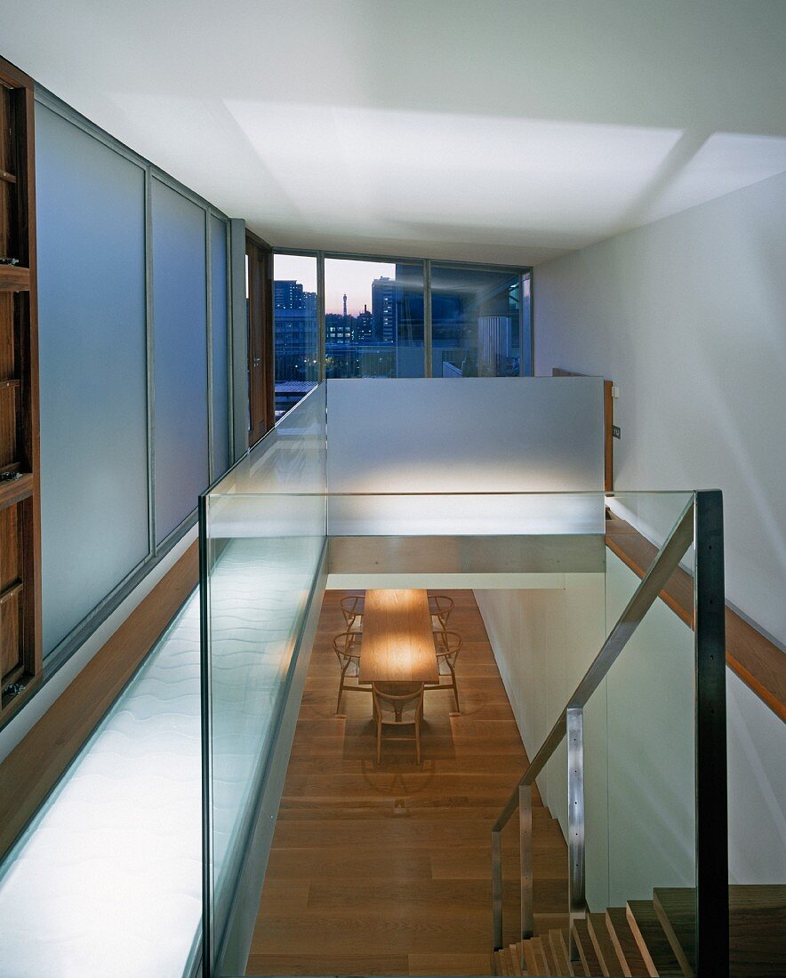 Fitted cupboards with sliding doors on gallery and stairwell with glass balustrade and view of living space