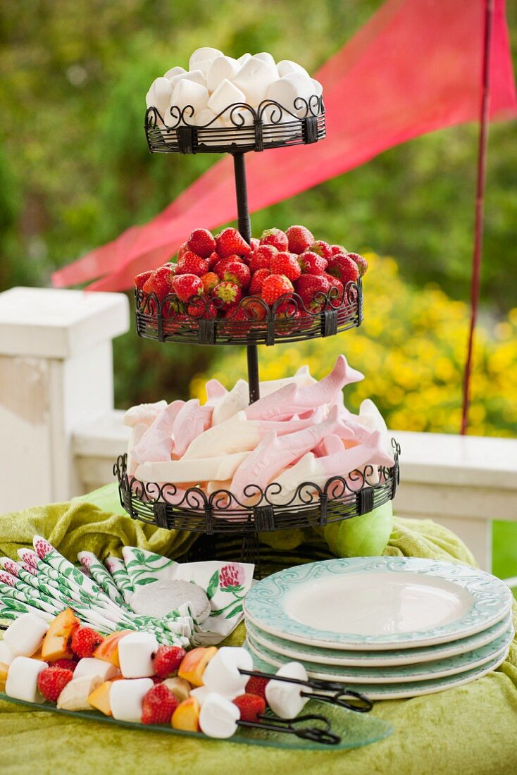Cake stand with marshmallows and strawberries on a table outside