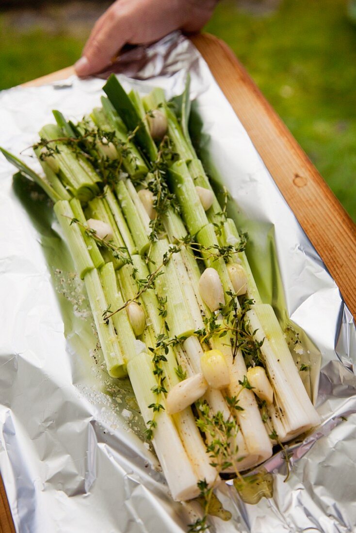 Leeks with thyme and garlic on aluminium foil (prepared for the barbecue)