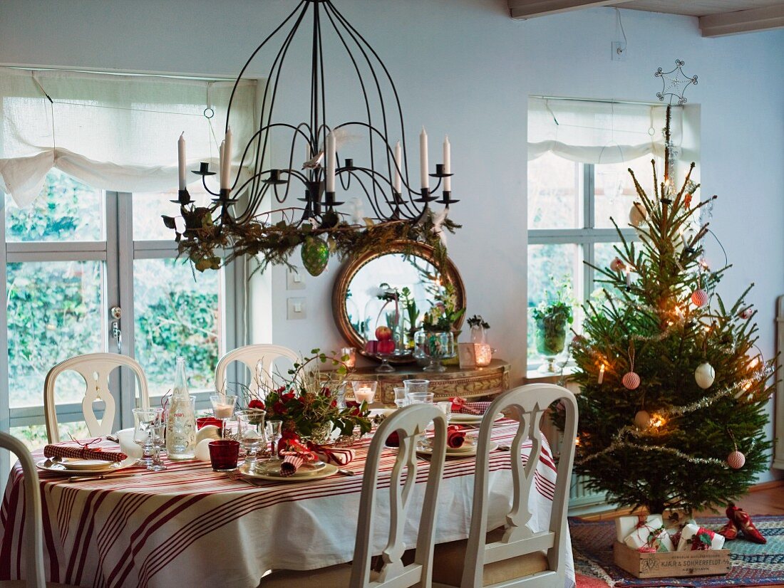 Festlich gedeckter Weihnachtstisch neben einem Weihnachtsbaum
