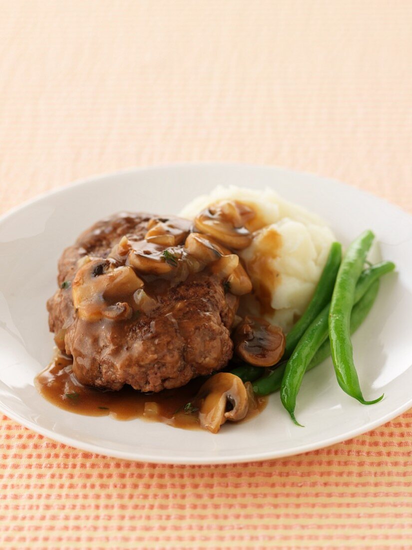 A burger with mushroom sauce, mashed potatoes and green beans