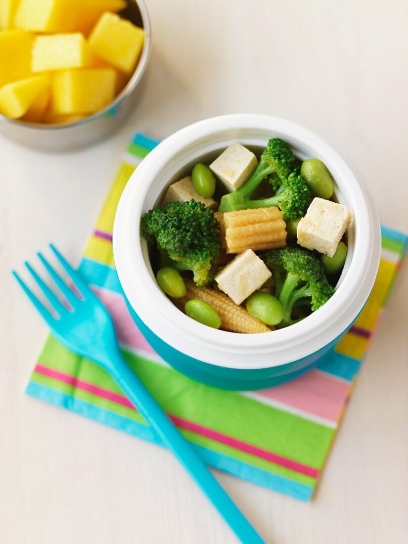 Vegetable salad with tofu and corn cobs in a plastic box