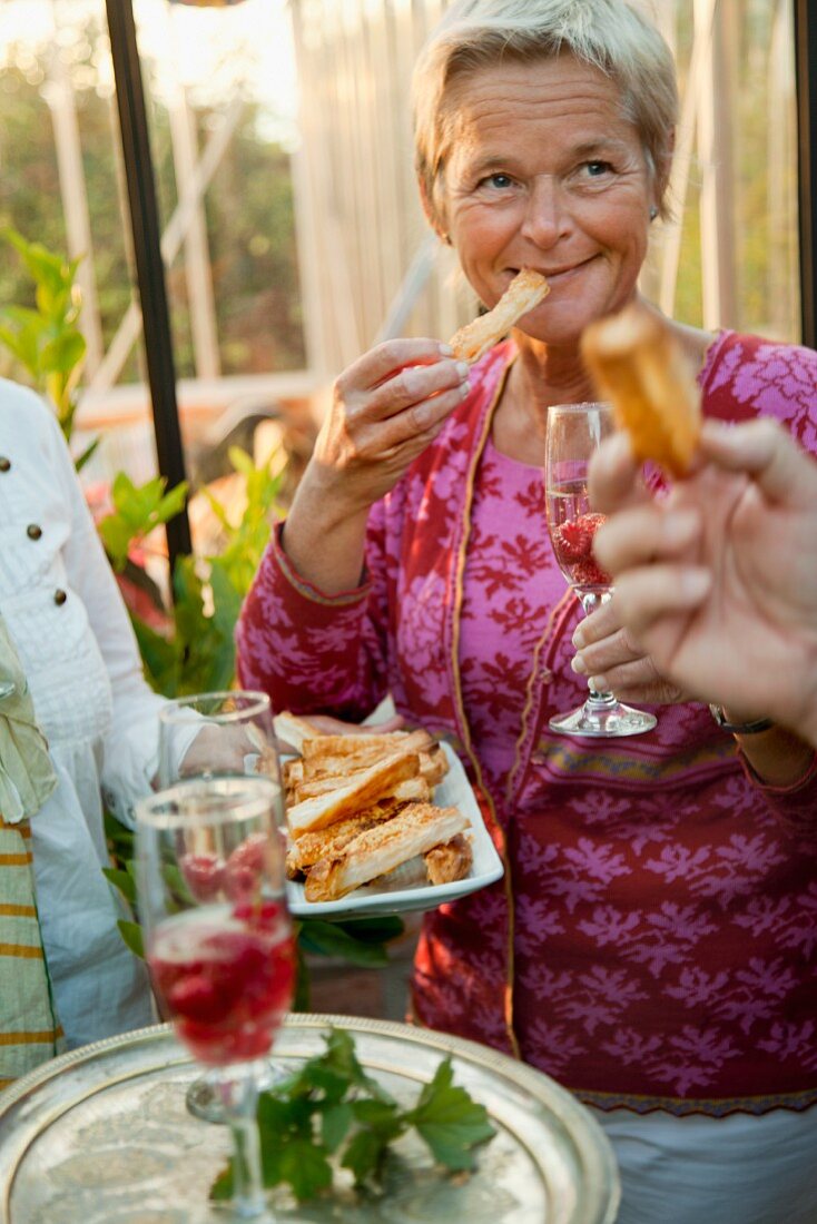 Blonde woman eating cheese pastry at a party