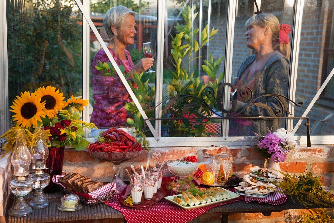 Partybuffet für das Krebsfest im Garten, im Hintergrund zwei ältere Damen