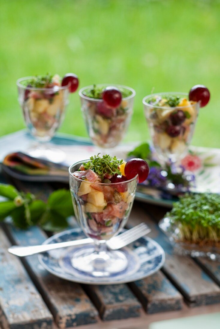 Potato and ham salad with grapes and cress in glasses