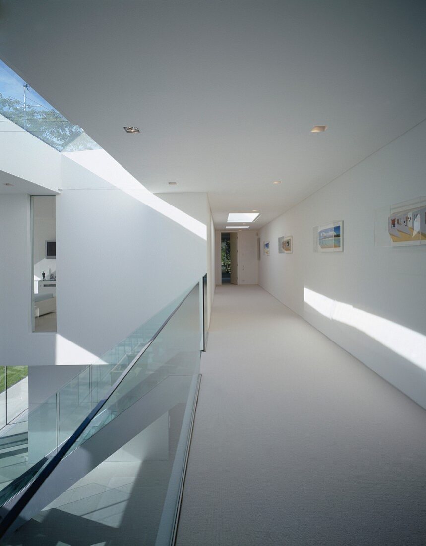 Long hall in upper storey, staircase with glass balustrade leads to ground floor