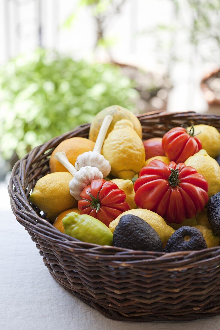 Korb mit Tomaten, Zitronen, Knoblauch und Avocado