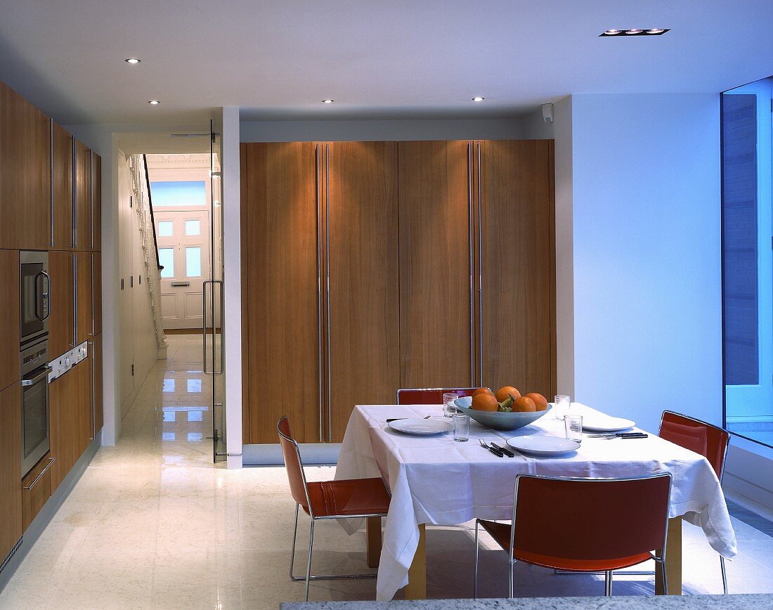 Table set with white tablecloth in front of fitted cupboard with wooden doors