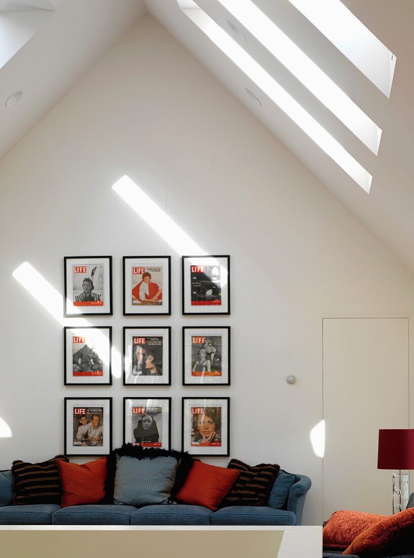 Collection of pictures above sofa with scatter cushions in attic storey with skylights