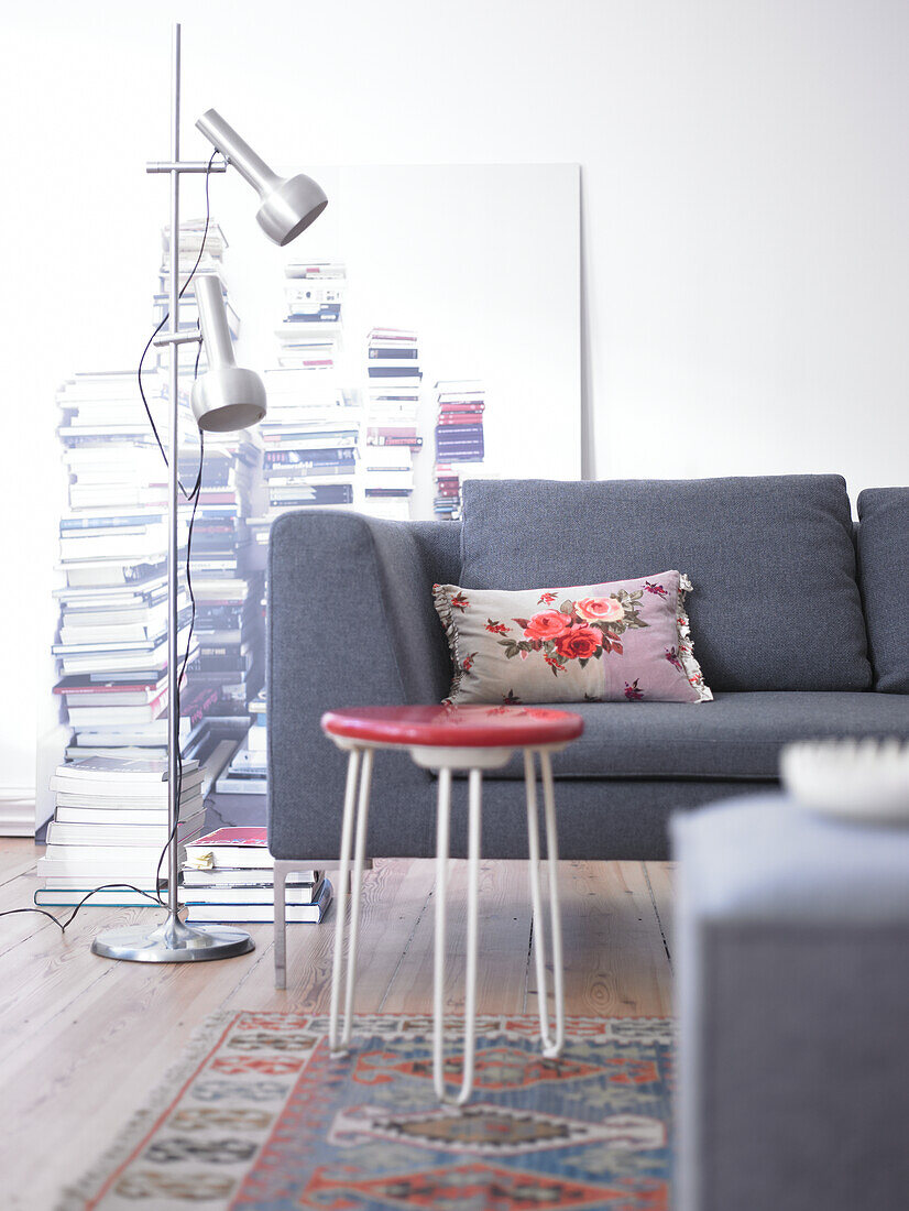 Grey sofa with floral cushion and red stool in living room