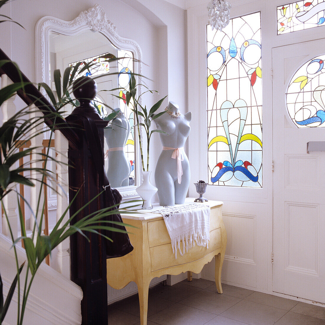 Entrance area with vintage console, stained glass windows and houseplant