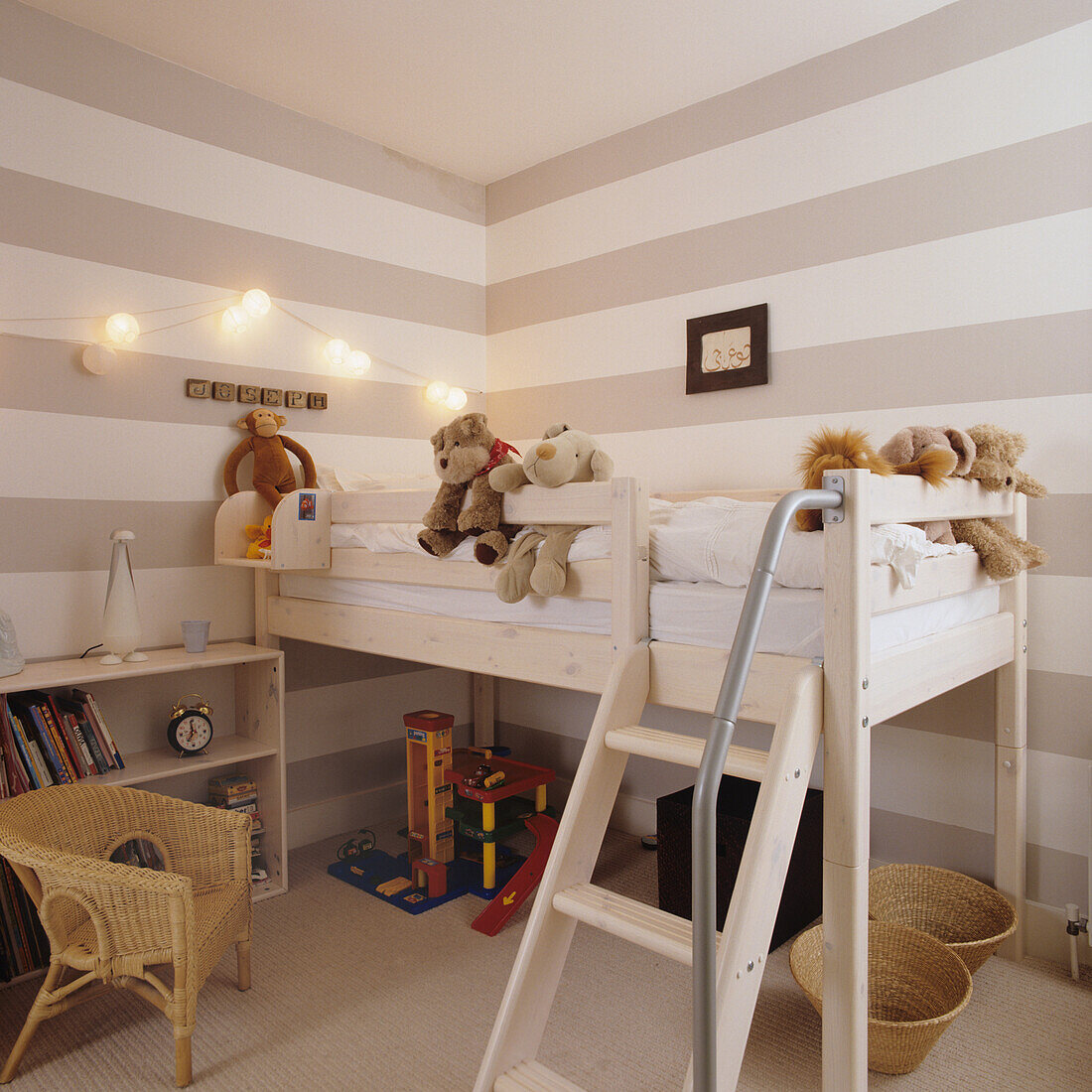 Loft bed with ladder in the children's room, striped walls and cuddly toys