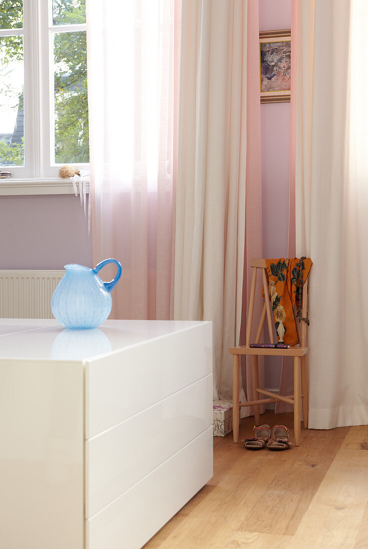 White half high drawer cabinet in a room and pink and white curtains at the window