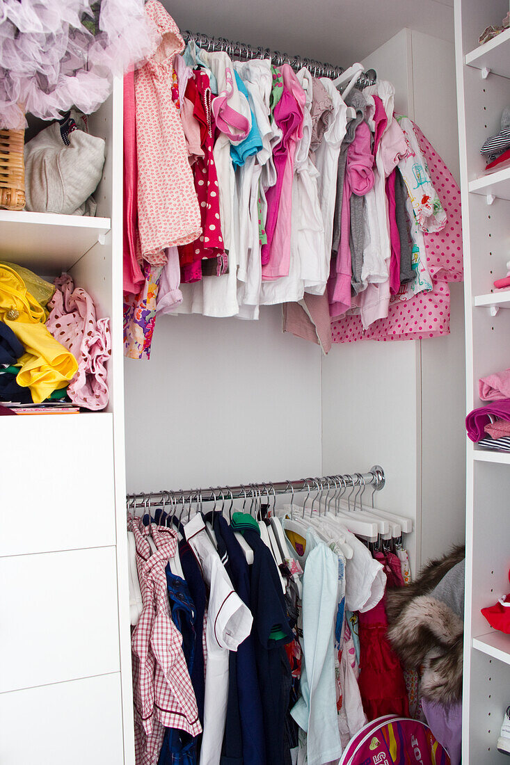 Overflowing children's wardrobe with colorful items of clothing