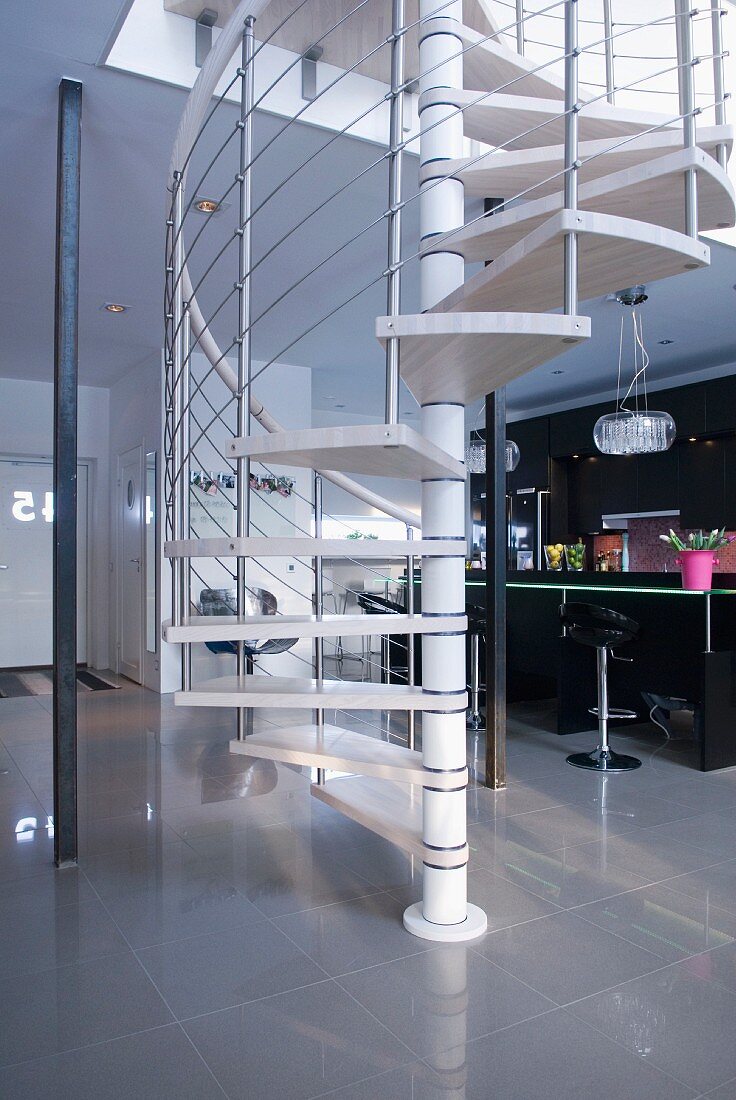 Modern curved staircase in an open living area in front of a black designer kitchen