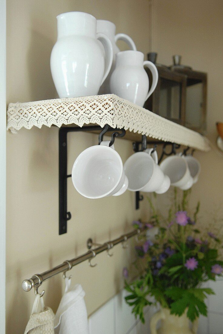 White china jugs and mugs on wall bracket with lace border