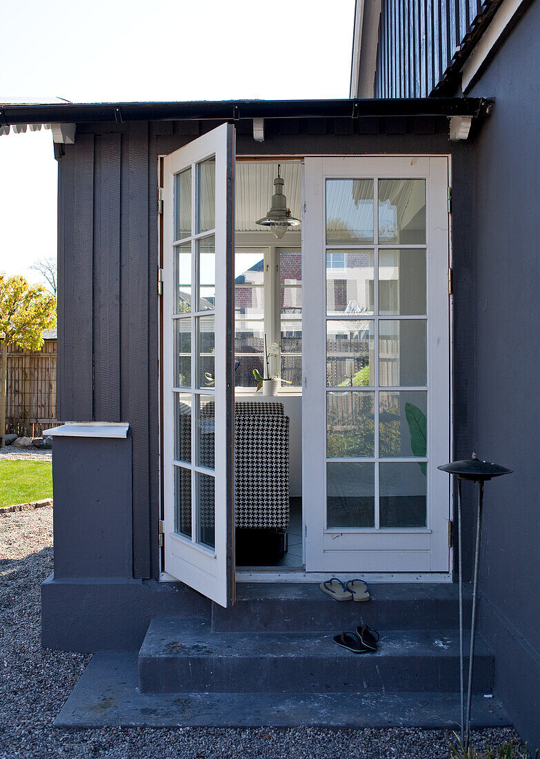 Open patio door with view of black and white sofa