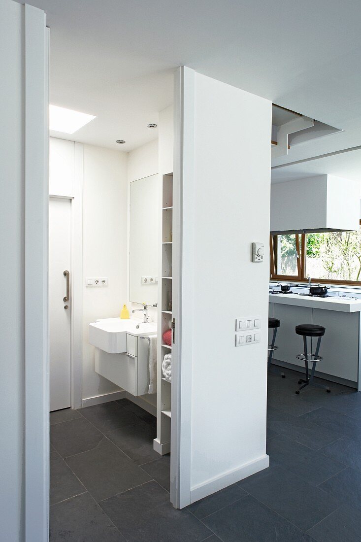 View into bathroom with white fittings and dark slate floor