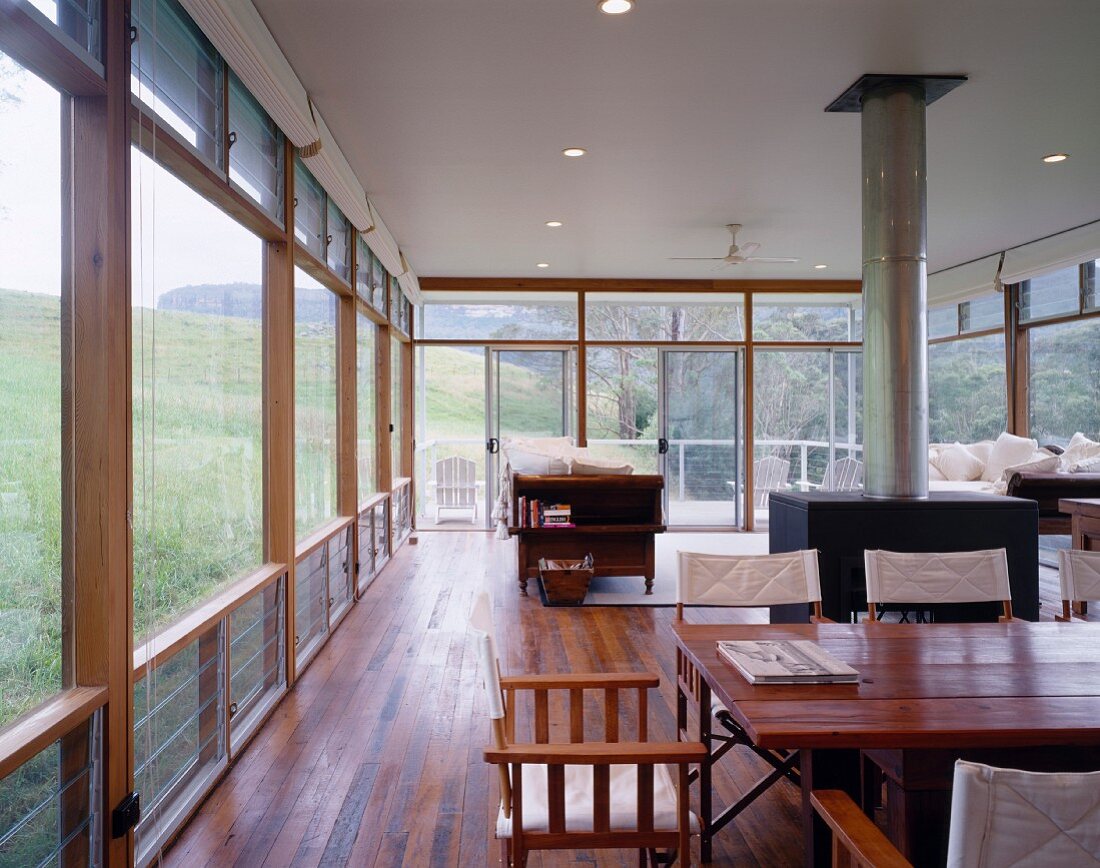 Open-plan living space in natural setting with wooden table and large wood-burning stove