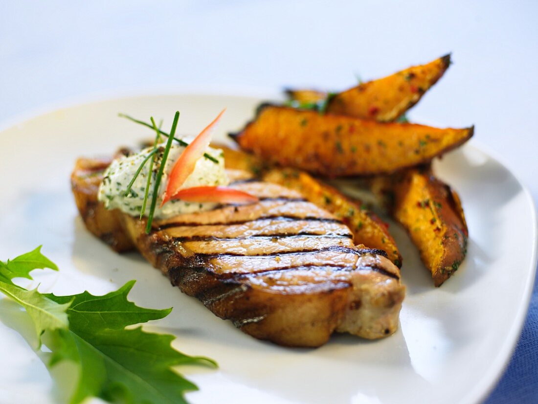 A grilled chop with herb butter and potato wedges