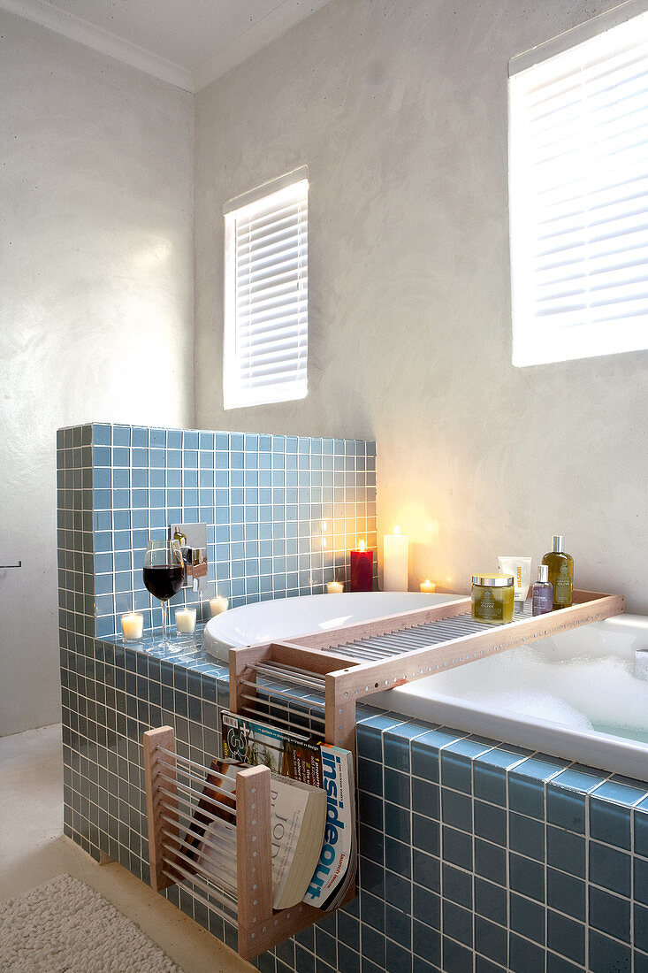 Blue-tiled bathtub with half-height partition in simple bathroom