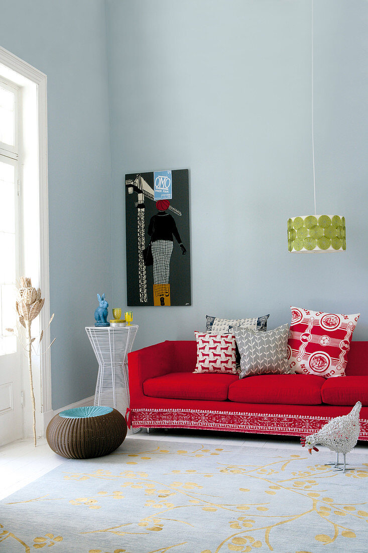 Cushions on red sofa and pendant retro lamp in minimalist living room