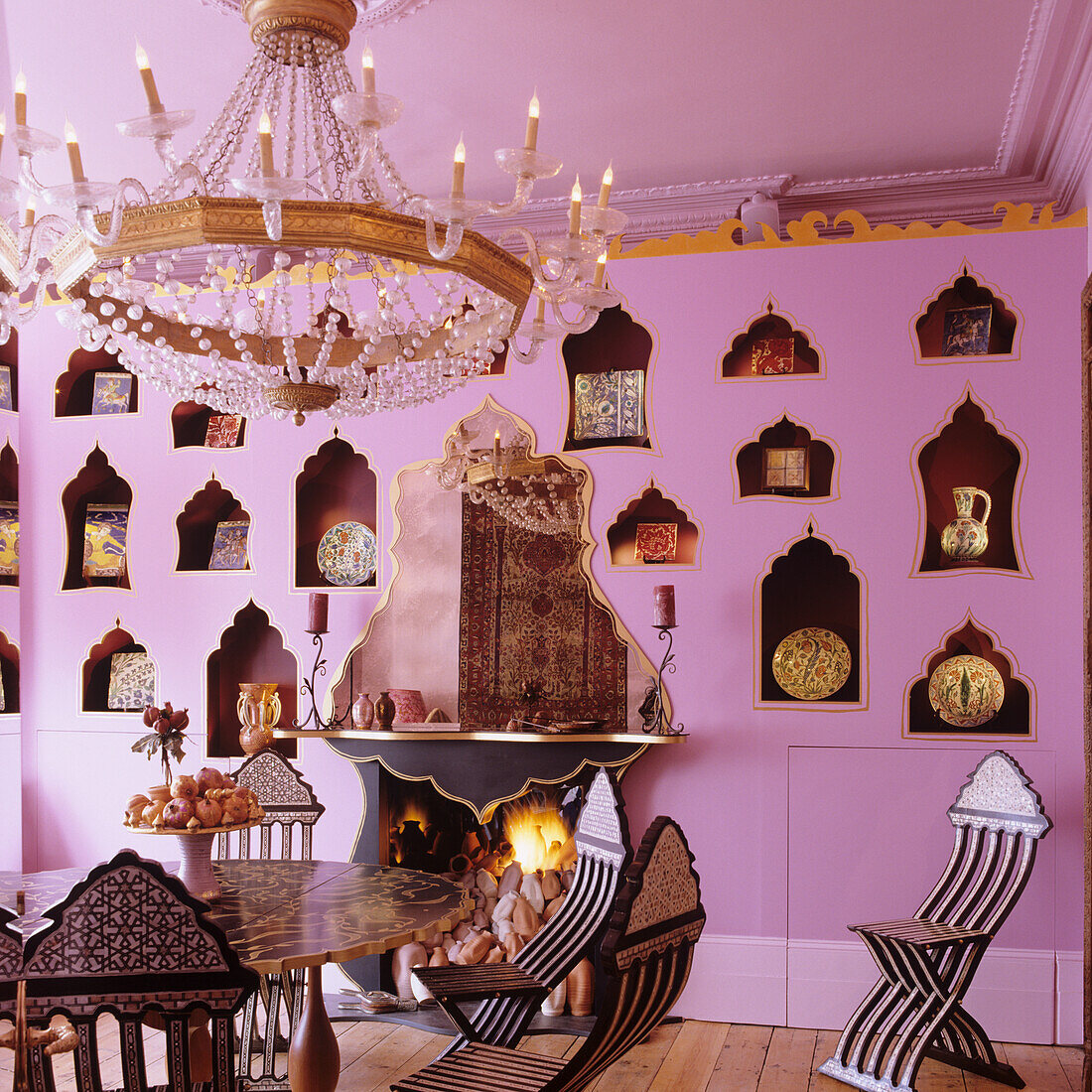 Dining room with pink wall, oriental-style wall niches and chandelier