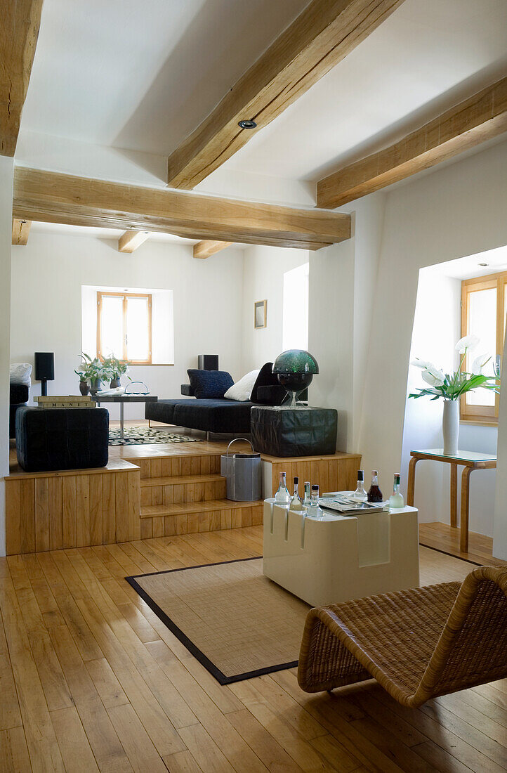 Living room with wooden beamed ceiling, modern furniture and lounge area on a platform