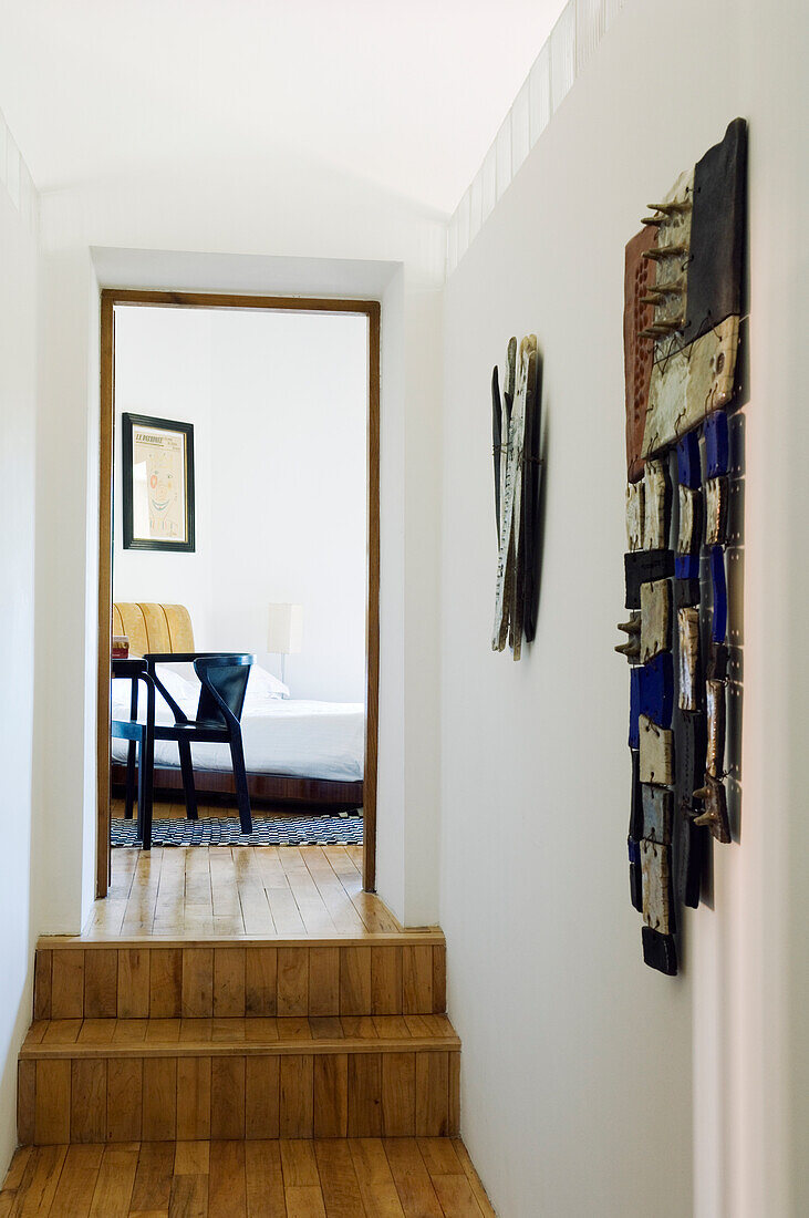 Hallway with wooden floor, steps and wall decoration, view into the bedroom