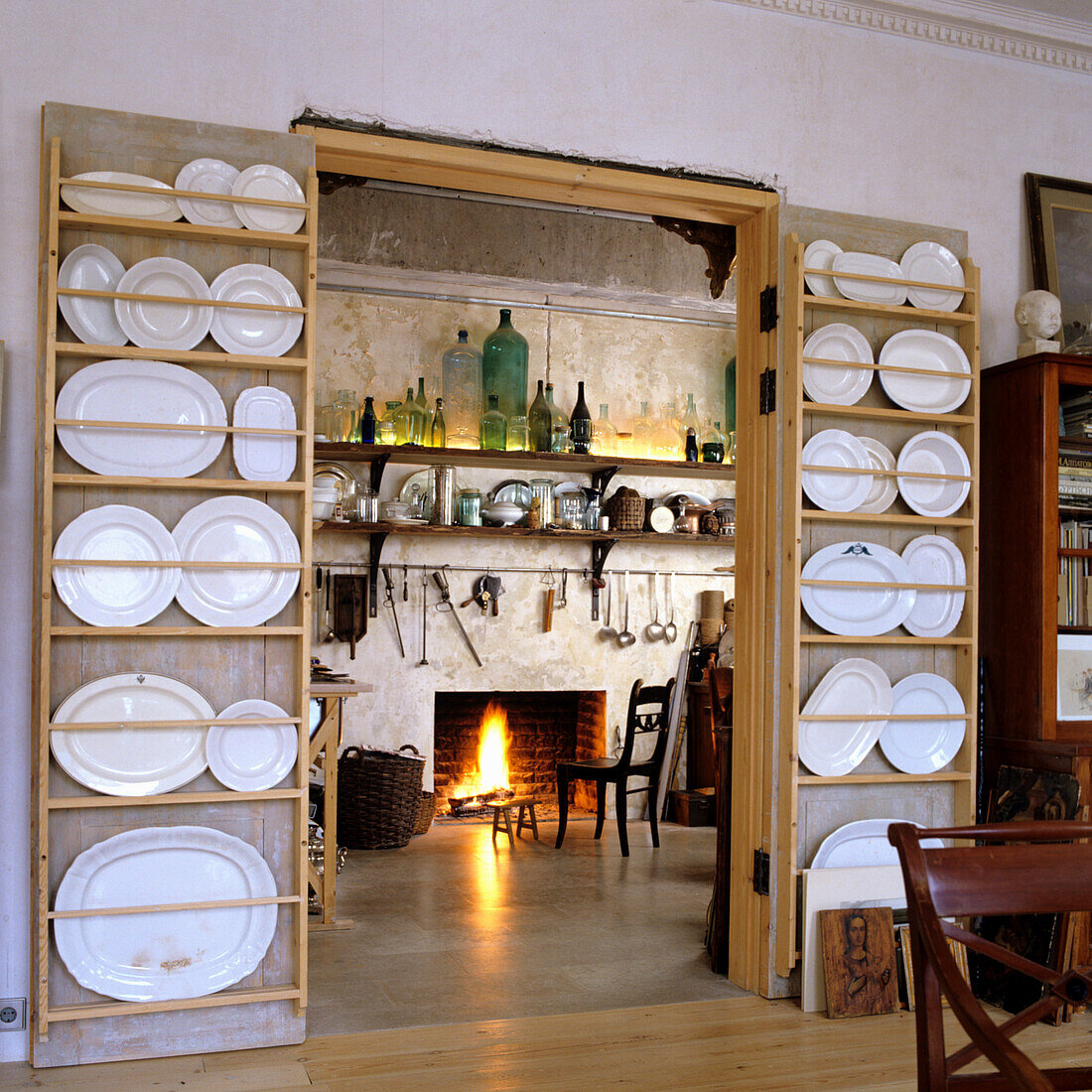 View of fireplace, plates and platters on plate rack