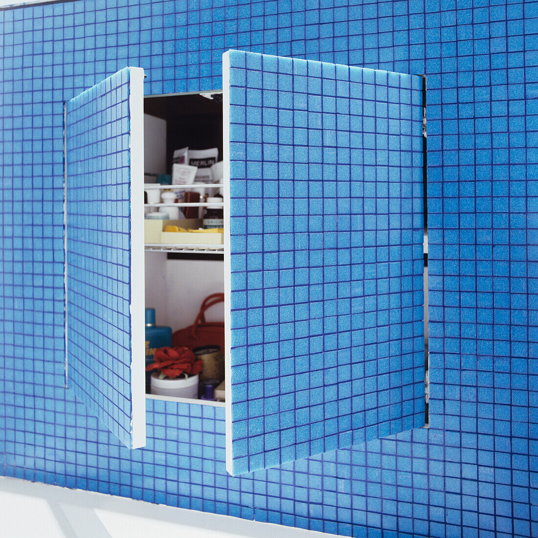 Small wall cabinet with open doors in blue tiled bathroom