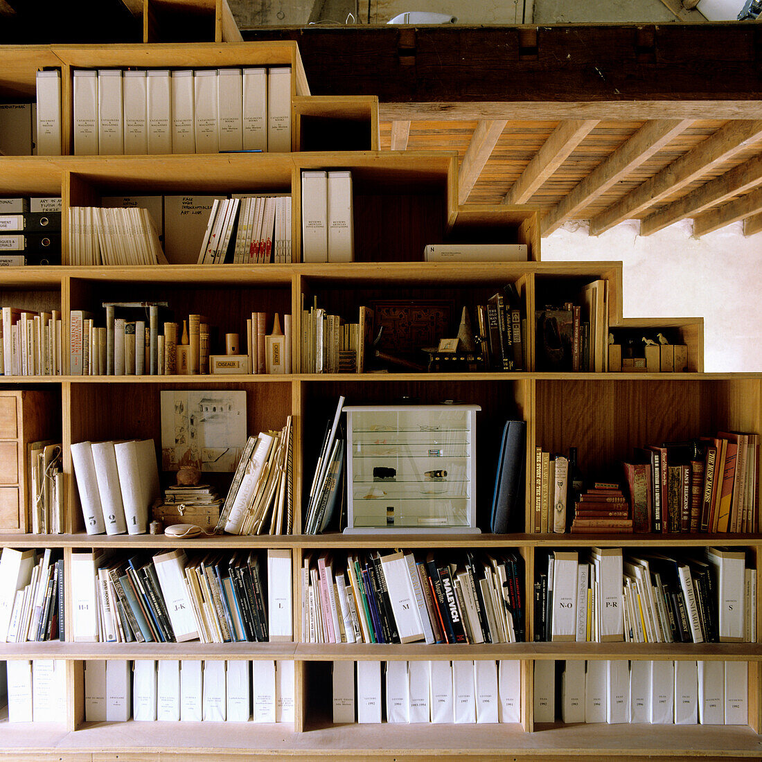 Large wooden bookshelf with files and books under beamed ceiling