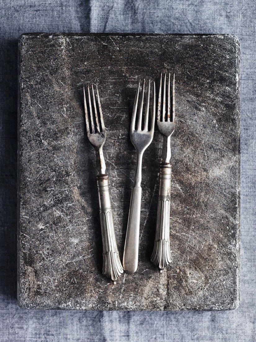 Three forks on a stone platter (seen from above)