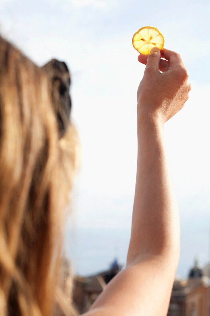 A woman holding a slice of lemon