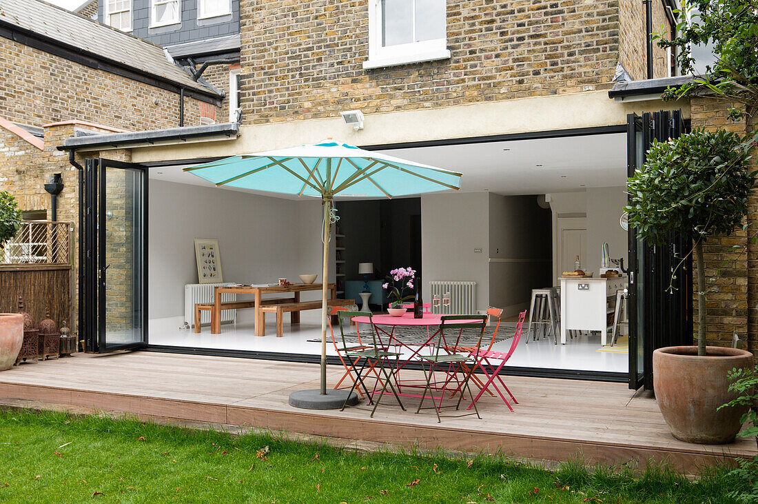 View of terrace with parasol, folding sliding doors and living area